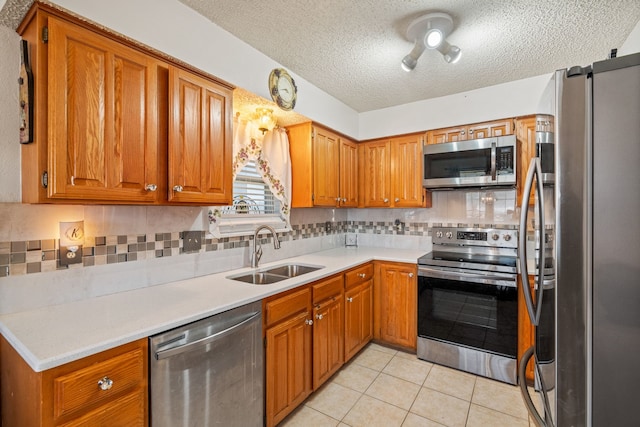 kitchen featuring light tile patterned floors, stainless steel appliances, a sink, and brown cabinets