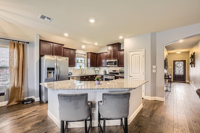 kitchen featuring visible vents, a sink, arched walkways, appliances with stainless steel finishes, and dark brown cabinets