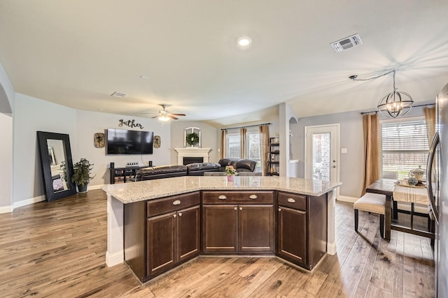 kitchen featuring light wood-style floors, visible vents, dark brown cabinetry, and a fireplace