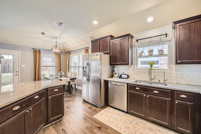 kitchen with visible vents, a sink, decorative backsplash, stainless steel appliances, and light wood-type flooring