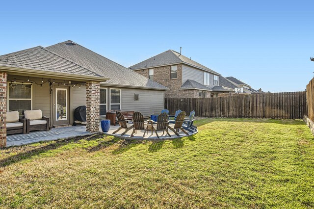 rear view of property featuring a patio, a lawn, a fenced backyard, and a shingled roof