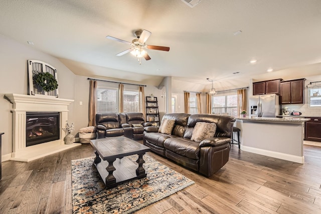 living room with baseboards, recessed lighting, ceiling fan, wood-type flooring, and a glass covered fireplace