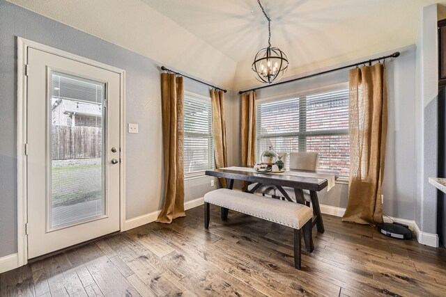 dining room with a chandelier, vaulted ceiling, baseboards, and hardwood / wood-style floors