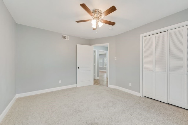 unfurnished bedroom featuring light carpet, a closet, visible vents, and baseboards