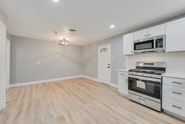 kitchen featuring baseboards, visible vents, light wood-style flooring, appliances with stainless steel finishes, and light countertops