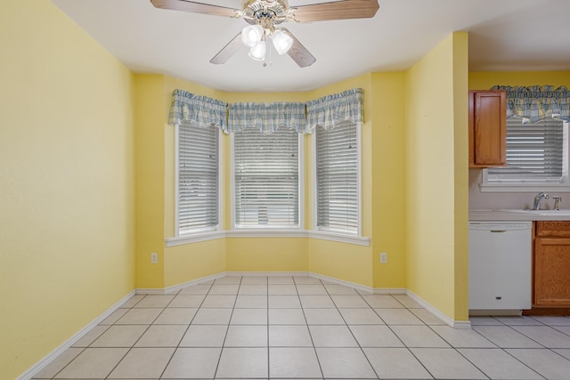 unfurnished dining area with a sink, light tile patterned floors, baseboards, and a ceiling fan