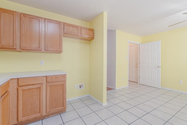 kitchen with light tile patterned floors, light brown cabinets, baseboards, and light countertops