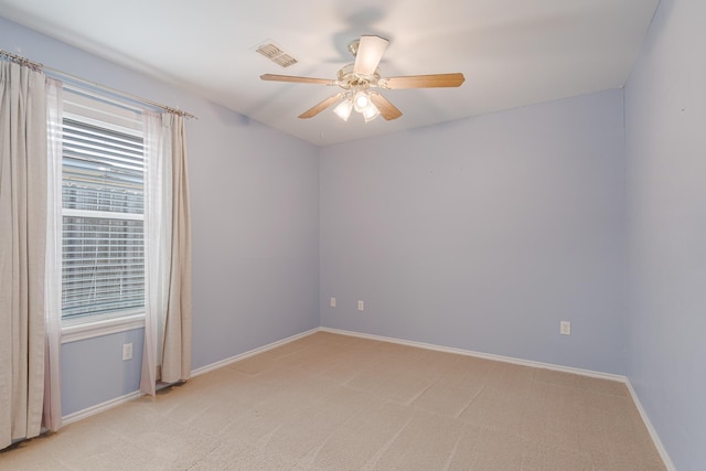 empty room with baseboards, light carpet, visible vents, and a ceiling fan