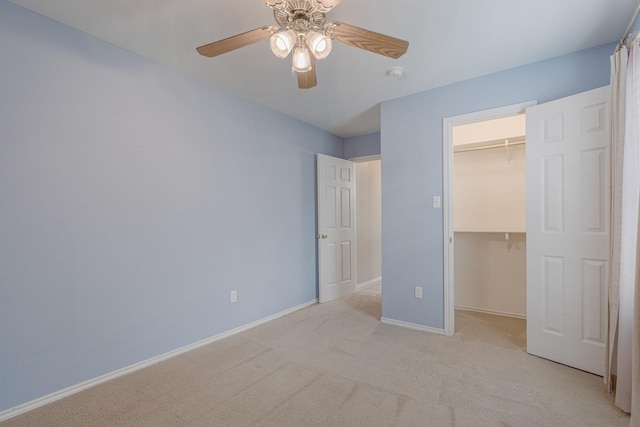 unfurnished bedroom with baseboards, a walk in closet, a closet, and light colored carpet