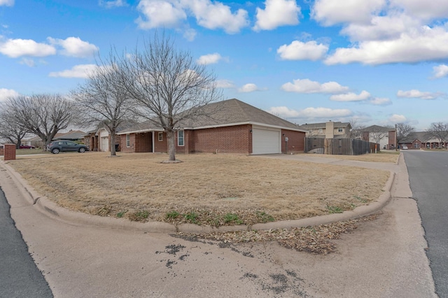 ranch-style home featuring concrete driveway, a residential view, an attached garage, fence, and brick siding