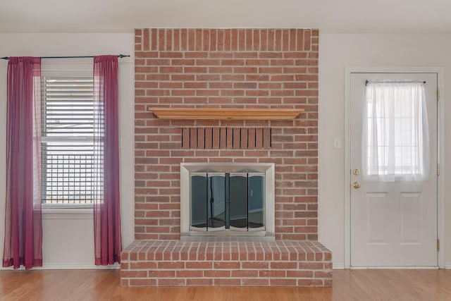 unfurnished living room with a brick fireplace and wood finished floors