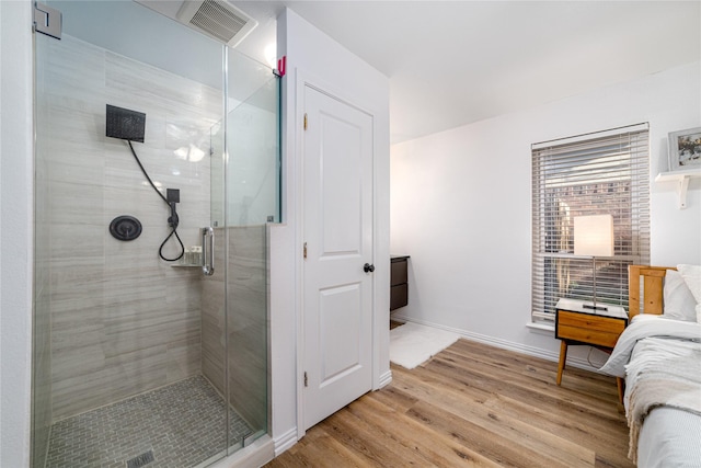 full bath with a stall shower, visible vents, baseboards, and wood finished floors