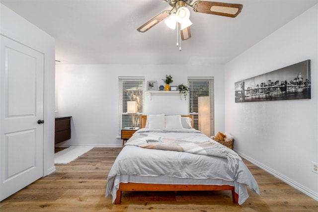 bedroom with ceiling fan, baseboards, and wood finished floors