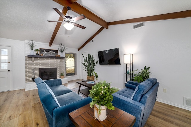 living room with lofted ceiling with beams, visible vents, plenty of natural light, and a fireplace