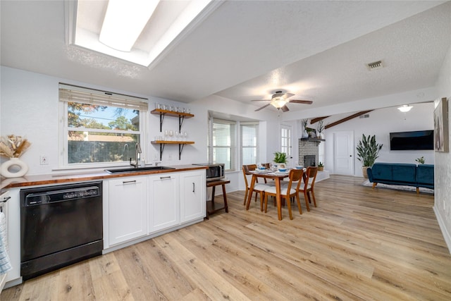 kitchen with visible vents, wooden counters, dishwasher, white cabinets, and a sink