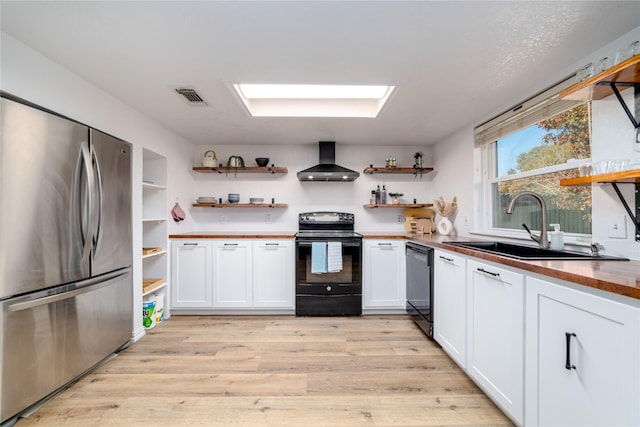 kitchen with visible vents, black range with electric cooktop, wall chimney range hood, freestanding refrigerator, and open shelves