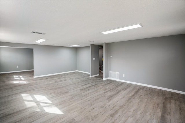 finished basement with visible vents, baseboards, and wood finished floors