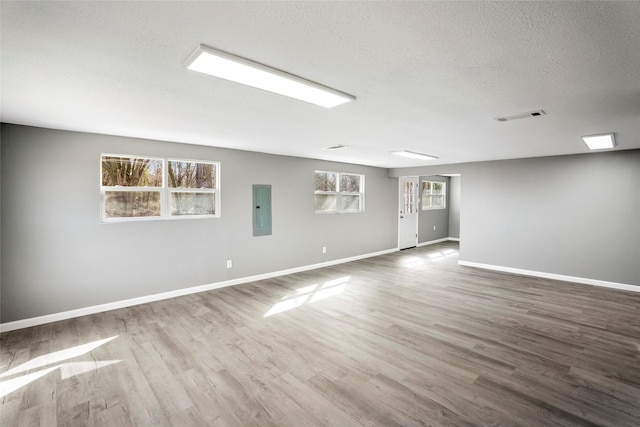 unfurnished room featuring electric panel, visible vents, baseboards, and wood finished floors