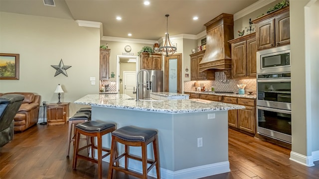 kitchen featuring stainless steel appliances, a sink, open floor plan, a center island with sink, and custom range hood