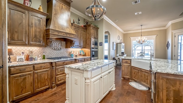 kitchen with arched walkways, stainless steel appliances, visible vents, custom range hood, and an inviting chandelier