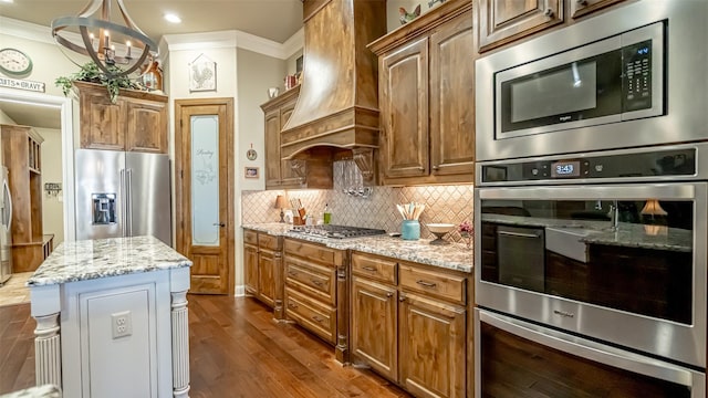 kitchen featuring stainless steel appliances, premium range hood, ornamental molding, and decorative backsplash