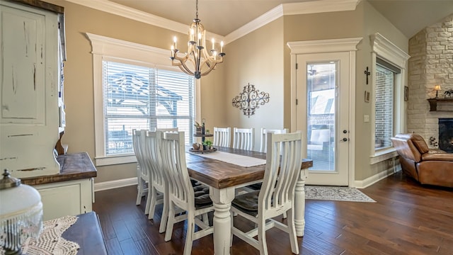 dining room featuring ornamental molding, a notable chandelier, dark wood finished floors, and a stone fireplace