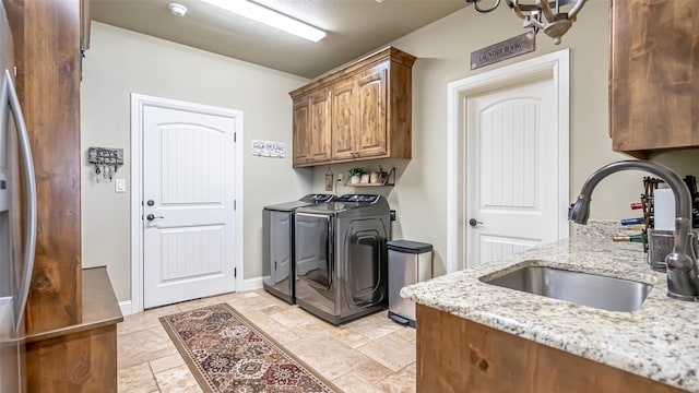 laundry area with cabinet space, baseboards, washer and clothes dryer, and a sink