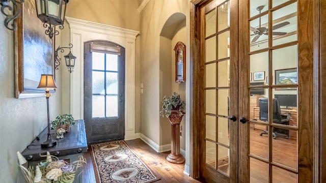 entryway featuring arched walkways, french doors, baseboards, and wood finished floors