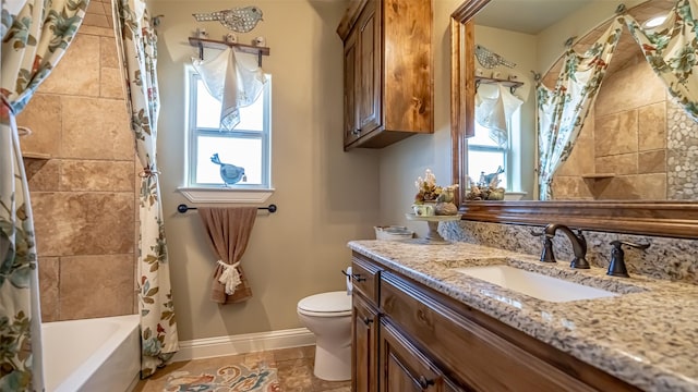 bathroom featuring baseboards, vanity, toilet, and a healthy amount of sunlight