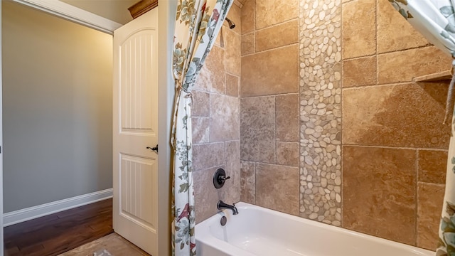 bathroom featuring shower / tub combo, baseboards, and wood finished floors