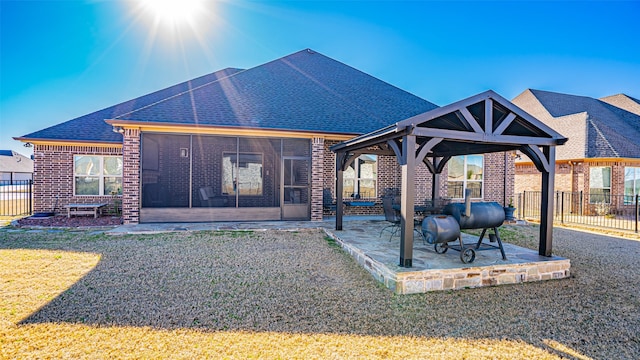 exterior space with brick siding, a patio, a lawn, a gazebo, and fence