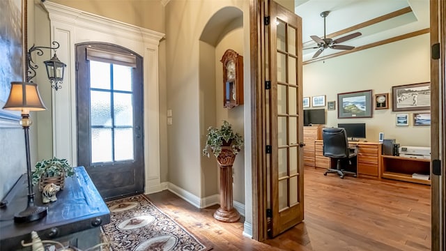 foyer entrance featuring light wood-type flooring, ceiling fan, arched walkways, and baseboards