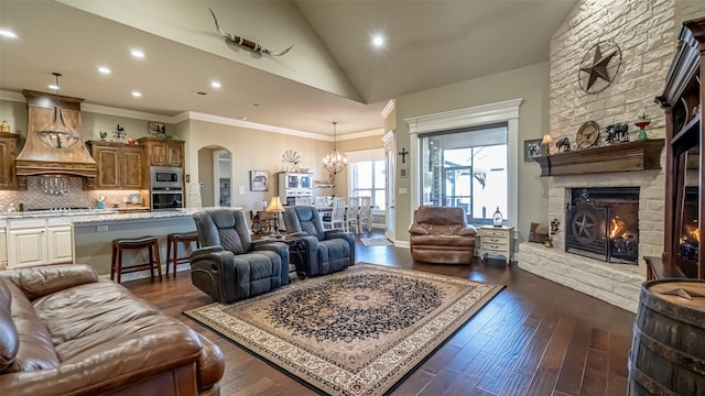 living room featuring arched walkways, a stone fireplace, dark wood-style flooring, and crown molding