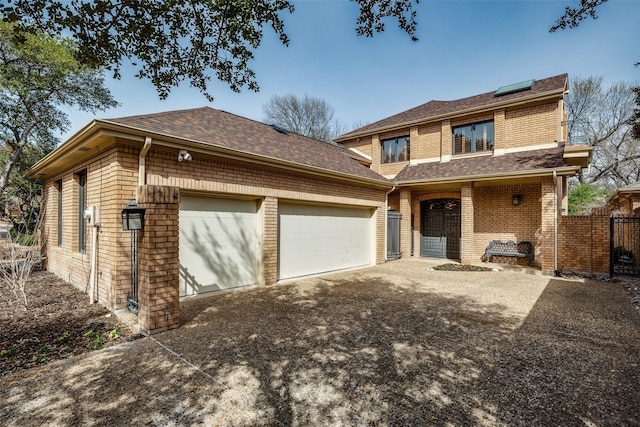 traditional-style house featuring driveway, roof with shingles, a garage, and brick siding