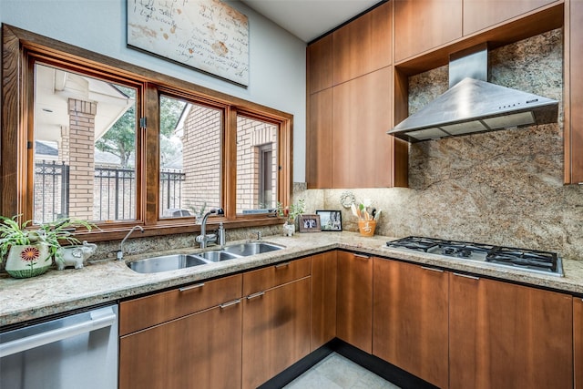 kitchen featuring appliances with stainless steel finishes, a sink, light stone countertops, wall chimney range hood, and backsplash