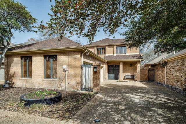 view of front of property featuring roof with shingles, fence, and brick siding