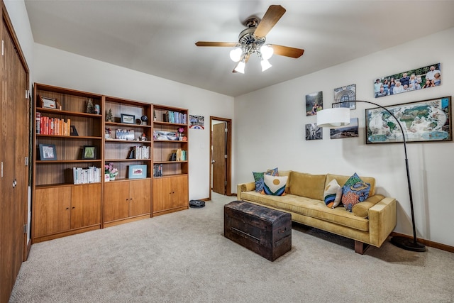 living area featuring ceiling fan, baseboards, and carpet flooring