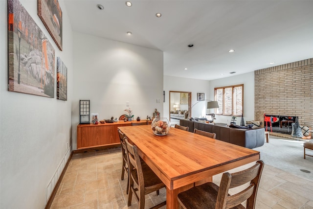 dining area featuring baseboards, a brick fireplace, recessed lighting, and stone tile floors