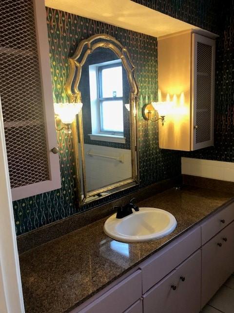 bathroom featuring vanity and wallpapered walls