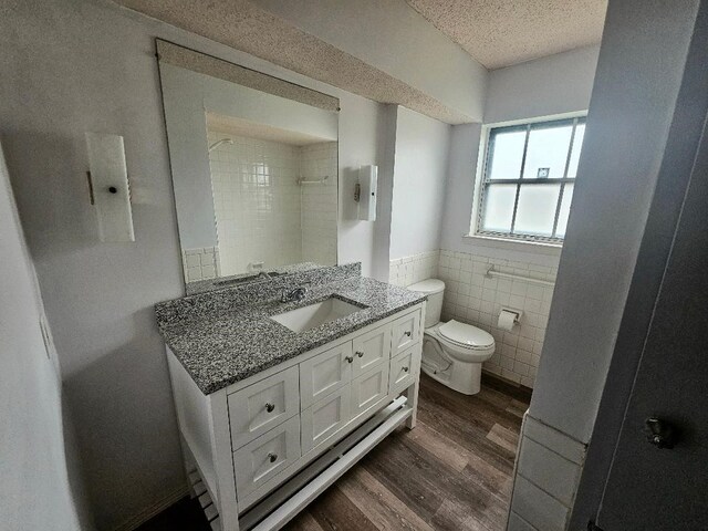 5825 Birchbrook Dr Unit 106, Dallas, TX 75206 - full bath with wood finished floors, tile walls, toilet, vanity, and wainscoting