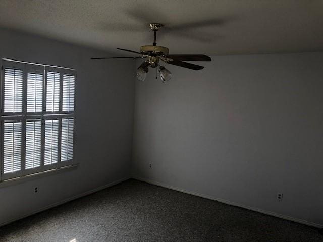 carpeted spare room featuring a ceiling fan, a wealth of natural light, a textured ceiling, and baseboards