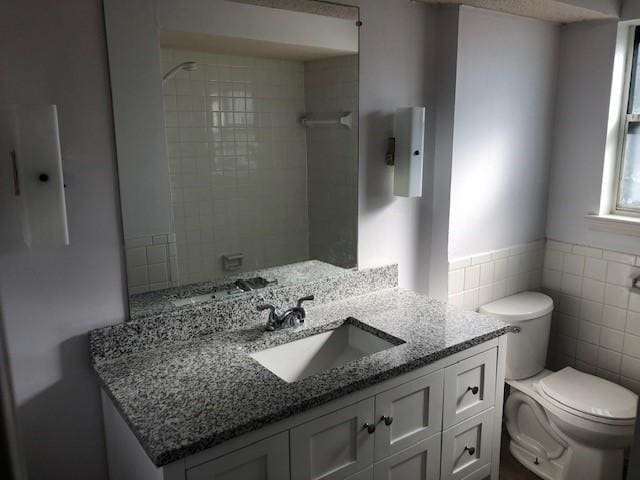 full bath with wainscoting, vanity, toilet, and tile walls