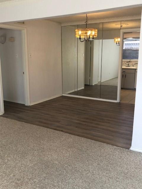 empty room with a sink, wood finished floors, and a notable chandelier