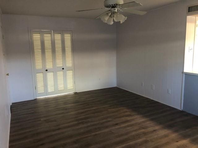 unfurnished room featuring visible vents, dark wood finished floors, and ceiling fan