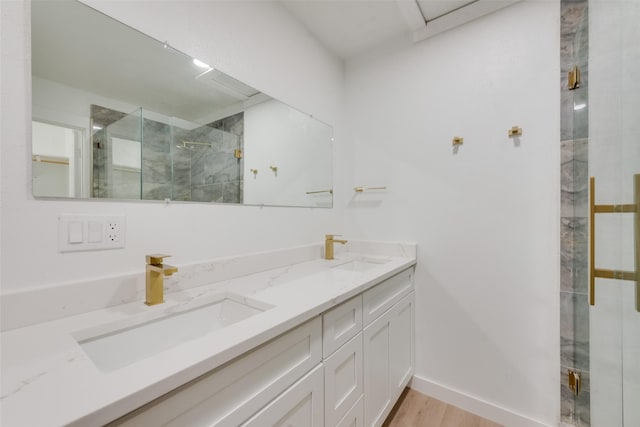 bathroom featuring double vanity, a stall shower, a sink, and wood finished floors