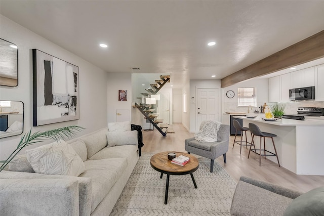 living room with light wood-style floors, recessed lighting, visible vents, and stairs