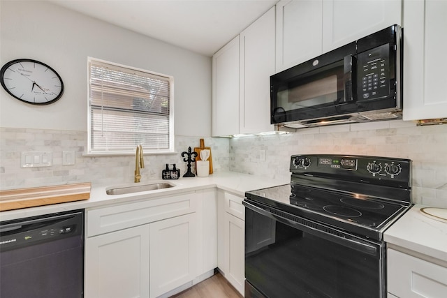 kitchen with tasteful backsplash, light countertops, white cabinets, a sink, and black appliances