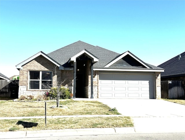 view of front facade with driveway, stone siding, fence, a shingled roof, and a garage