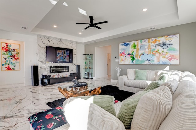 living room with recessed lighting, a premium fireplace, visible vents, marble finish floor, and a tray ceiling