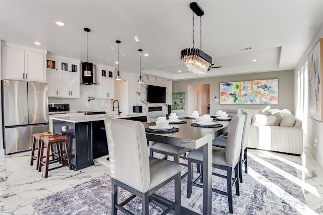 dining room featuring a tray ceiling, marble finish floor, visible vents, and recessed lighting